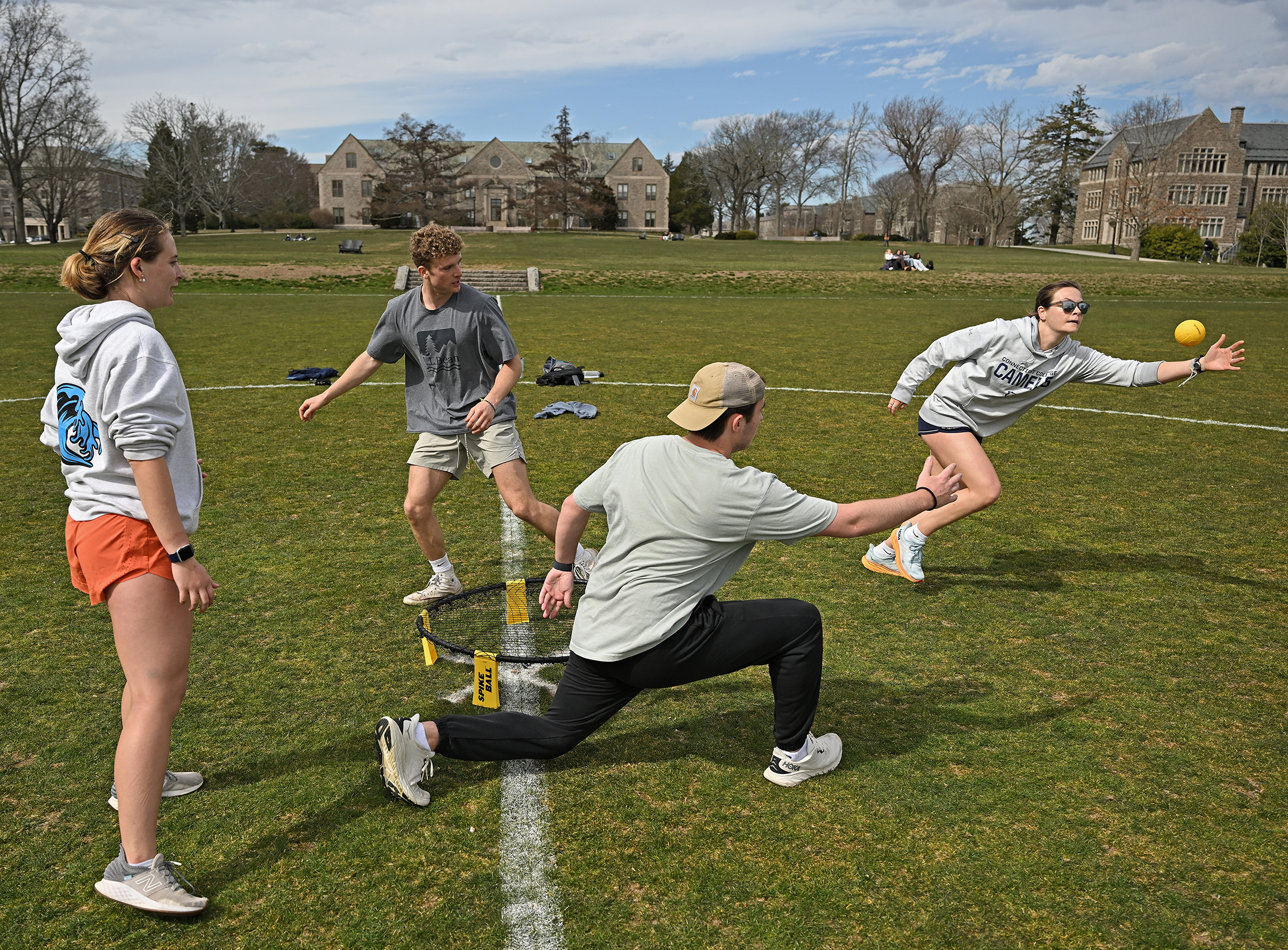 four students play a game of spikeball on the college green