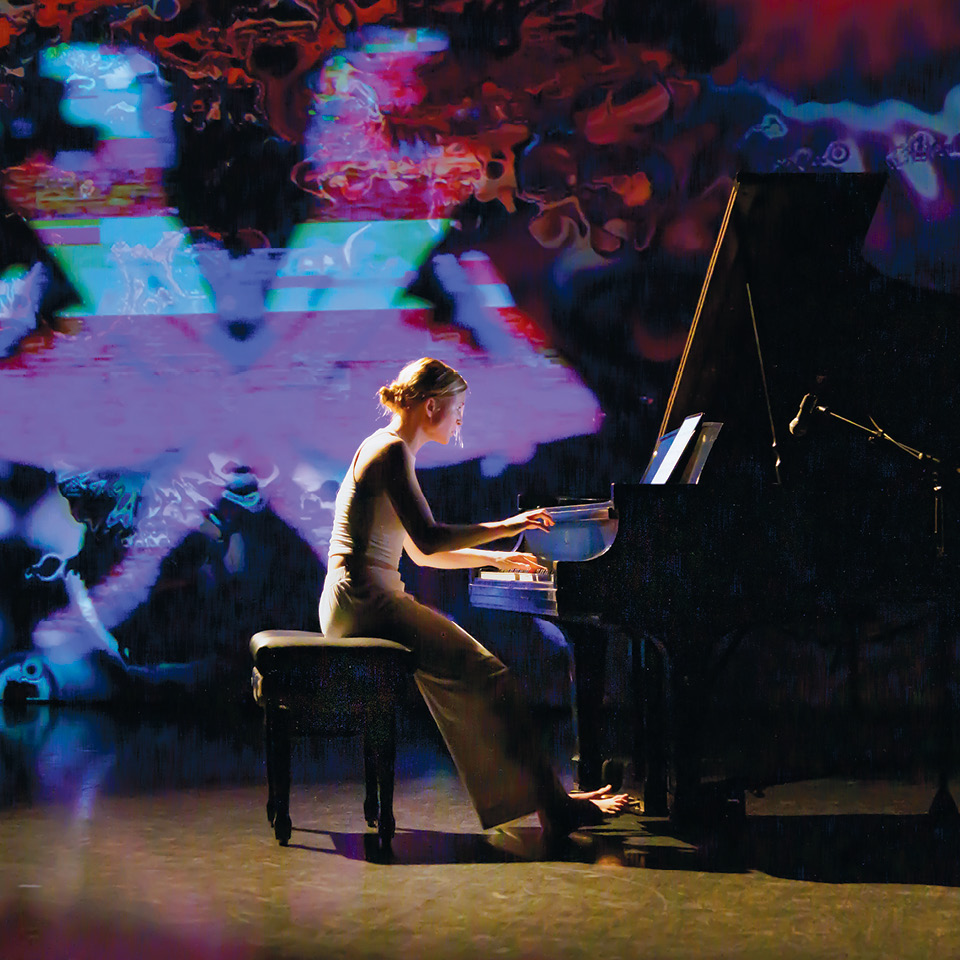 Student playing piano with colored lights in background