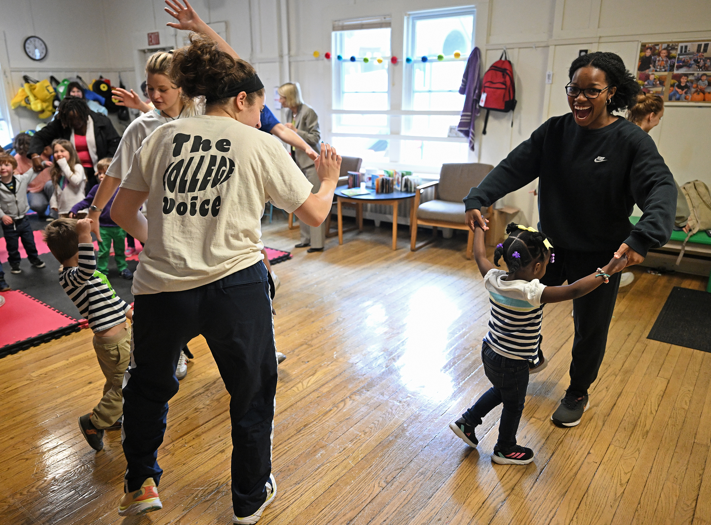 college students dance with preschoolers at a child care center