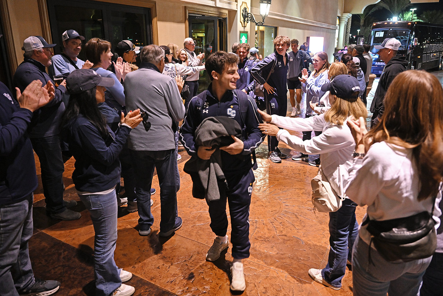 A crowd of fans greet a soccer team arriving back at the hotel after the game.