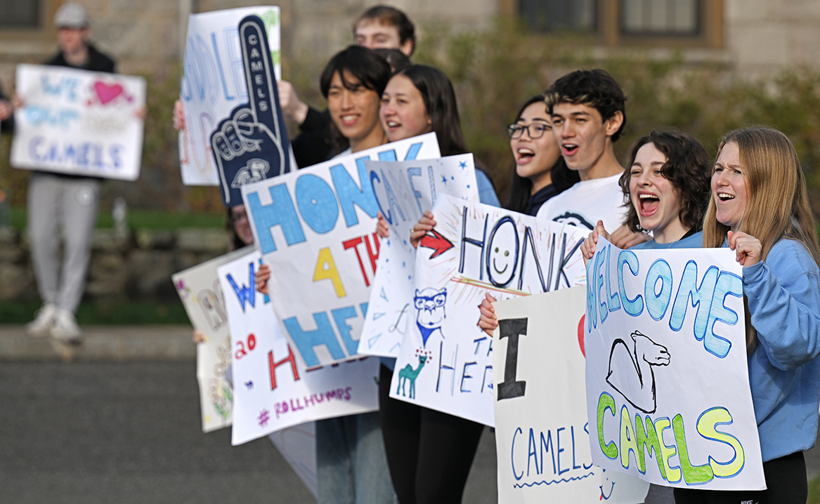 students holding signs cheer