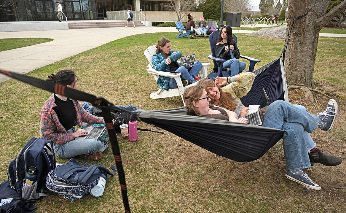 students, including two in a hammock, gather on a lawn area