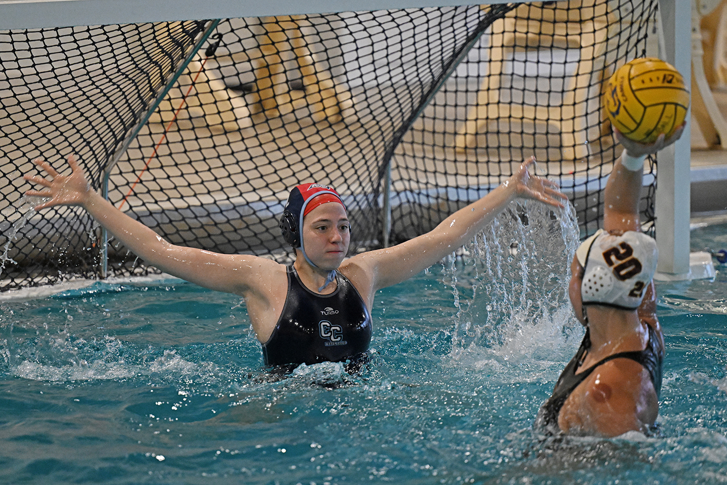 water polo goalie rises out of the water to defend the goal
