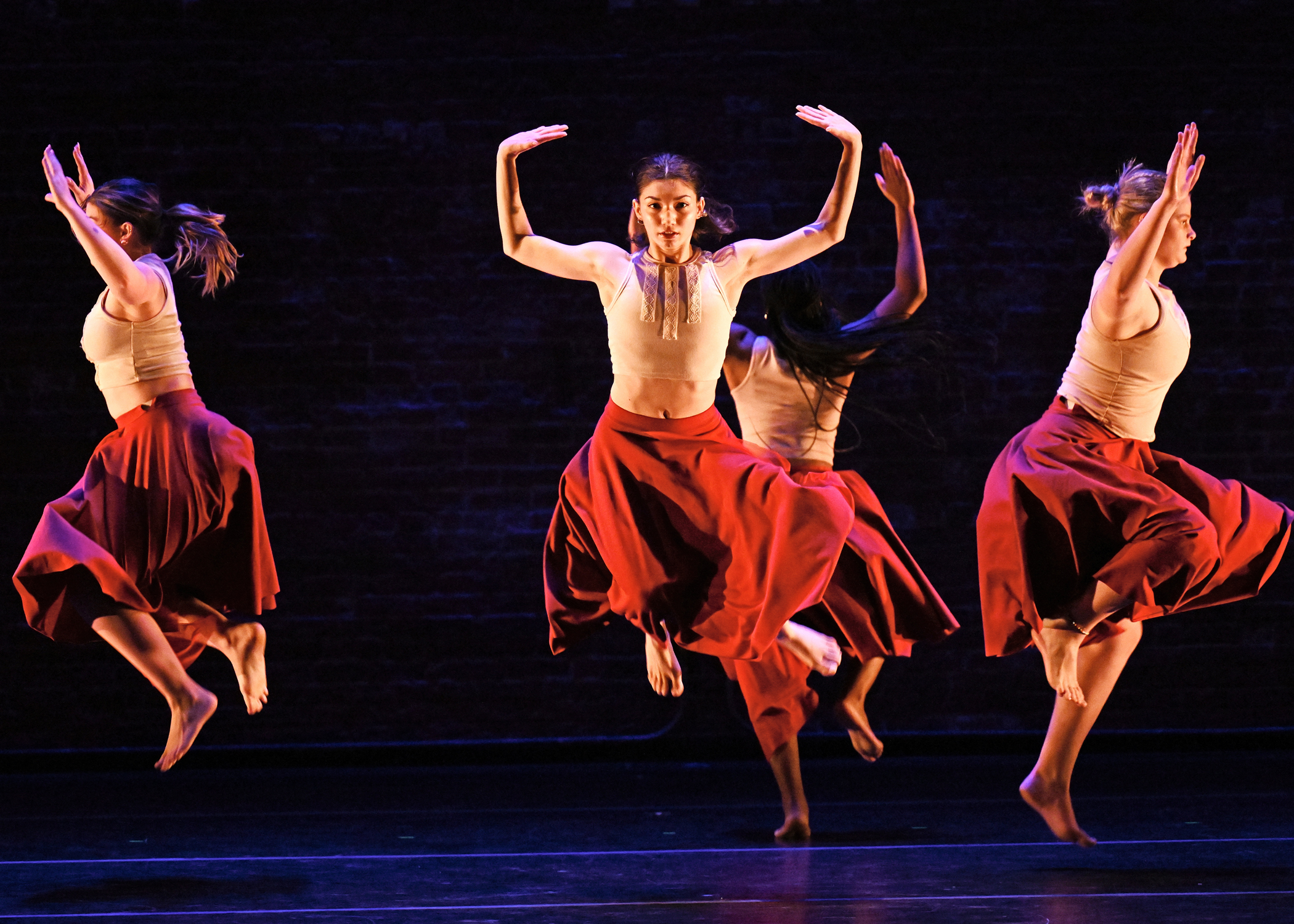 dancers in red dresses leaping in the air